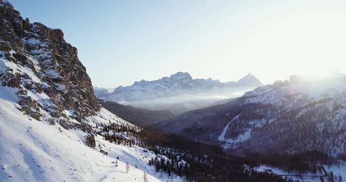 Forward aerial to snowy valley with woods forest at falzarego pass.Sunset or sunrise, clear sky.Winter Dolomites Italian Alps mountains outdoor nature establisher.4k drone flight