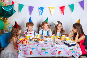 Group of joyful little kids celebrating birthday party at home. Children's funny birthday party in...