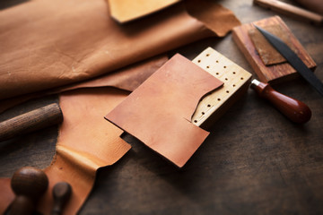 Leather craft or leather working. beautifully colored tanned leather on leather craftman's work desk with working tools.
