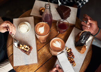 Friends eating desserts and drinking coffee together in a cafe