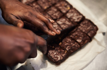 Baker slicing fresh brownies into squares in a cafe kitchen