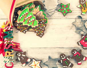 Obraz premium Beautiful Christmas composition and decoration with baked Christmas gingerbread cookies in paper bag on light wooden background, flat lay, top view, copy space (text space)