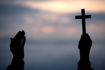 Silhouette of teen girl hands holding wooden cross on sunrise background, Crucifix, Symbol of Faith.