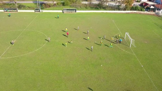 Aerial: Kids playing football game taking free kick and missing goal.