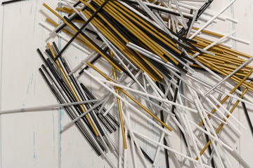 Table full of plastic straws in gold, silver, white and black
