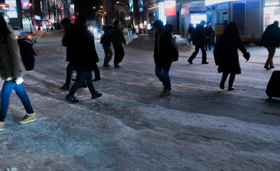 A pedestrian crossing the frozen road surface at night. January 2017 Sapporo city center Hokkaido,...