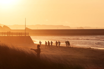 Gente corriendo por la playa al atardecer