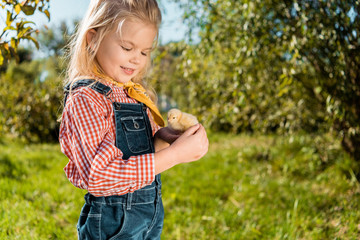 smiling little kid holding adorable yellow baby chick outdoors © LIGHTFIELD STUDIOS