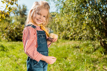 little kid holding adorable yellow baby chick and looking at camera outdoors © LIGHTFIELD STUDIOS