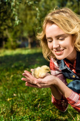 attractive woman holding adorable yellow baby chick outdoors