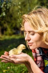 smiling woman holding adorable yellow baby chick outdoors