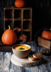 Fototapeta na wymiar Vegetarian pumpkin cream soup. Autumnal pumpkin soup. Home made pumpkin cream soup decorated with cream, seeds, bread