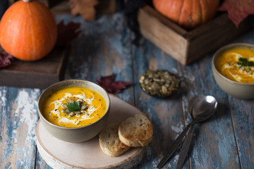 Vegetarian pumpkin cream soup. Autumnal pumpkin soup. Home made pumpkin cream soup decorated with cream, seeds, bread