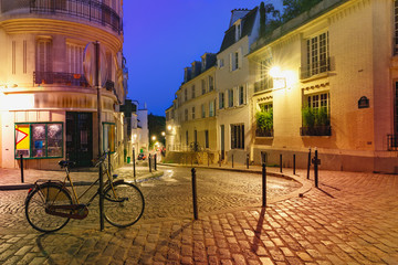 Empty cozy street with bike and street lamp at night, quarter Montmartre in Paris, France