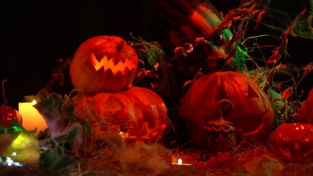 Scary voodoo shaman stares from behind carved pumpkins