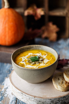 Vegetarian pumpkin cream soup. Autumnal pumpkin soup. Home made pumpkin cream soup decorated with cream, seeds, bread