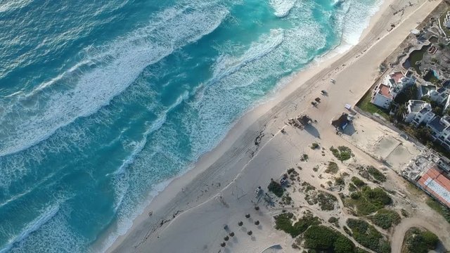 Aerial view of Cancun Mexico beach, drone is flying over the hotel zone making a reveal shot of the blue caribbean sea and the horizon on a sunny day