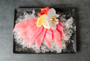 Sashimi of tuna on ice ice with flower and lemon