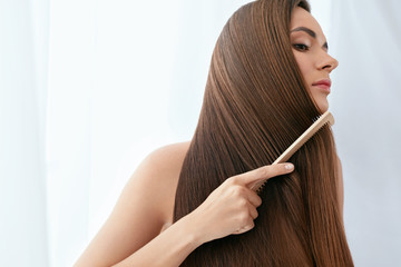 Hair Care. Woman Combing Beautiful Long Hair With Wooden Brush