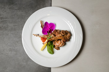 Rack of lamb with flowers on a white plate