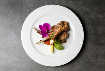 Rack of lamb with flowers on a white plate