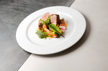 Duck fillet with figs and carrot puree on a white plate