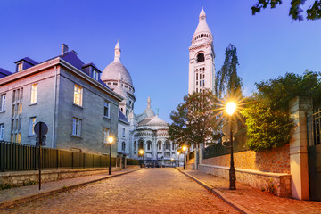 Empty cozy street and the Sacre-Coeur Basilica during morning blue hour, quarter Montmartre in...