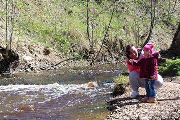 Walk daughter with her mother on the nature near the water.