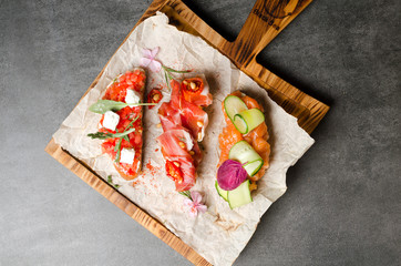 Assorted bruschetta with salmon Parma ham and tomatoes on a wooden board