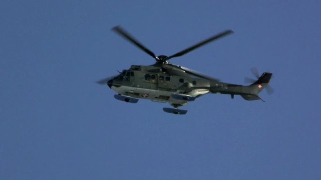 Black helicopter flying against the blue sky