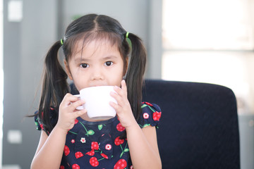 Asian child cute or kid girl delicious hot cocoa or chocolate and milkshake drink with holding...