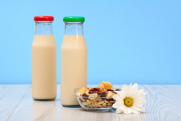 Two bottles of milk with red and green cap and bowl with muesli