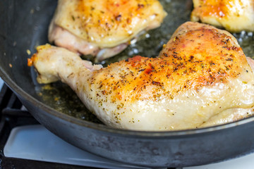 Fry chicken legs in a pan with spices.