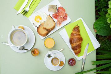 French breakfast in small cafe with inner garden. Coffee, croissant, marmelade, orange juice and...