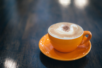 A orange cup of coffee on wooden background