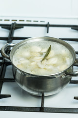 dumplings are cooked in a pot on a gas stove.