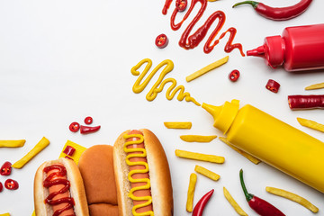 top view of tasty hot dogs and fries with mustard and ketchup on white surface