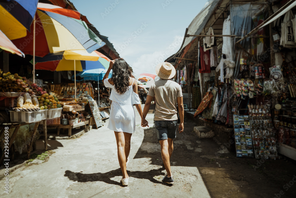 Wall mural couple enjoying their time looking for souvenir in the market