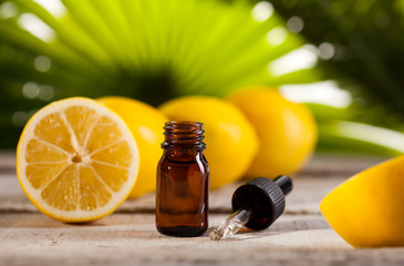 Lemon Essential Oil on green leaves background