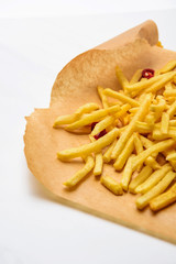 delicious french fries with spicy peppers on parchment paper on white
