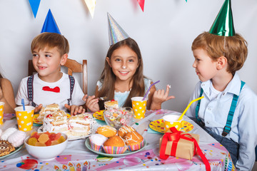 Happy childrens having fun and eating cake at birthday party