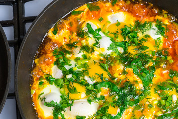 Cook shakshuka on a gas stove in a frying pan.