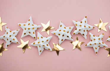 White and gold star decorations on a pastel pink. Seasonal festive background