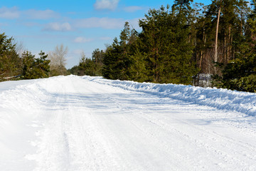 Fototapeta na wymiar Road in a countryside in sunny winter day. Classic snow covered winter landscape