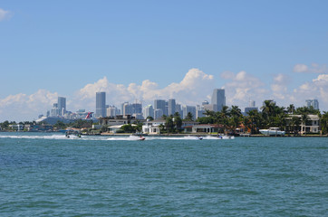 View looking west from a vantage point in Miami Beach of jet skiers on the Florida Intra-Coastal Waterway,expensive island home on Rivo Alto in Miami Beach and the Miami skyline.