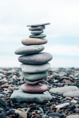 Fototapeta na wymiar relaxation at sea. Stack of stones on beach - nature background. Stone cairn on green blurry background, pebbles and stones