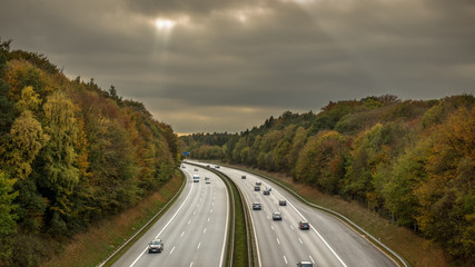 Autobahn durch eine herstfarbende Landschaft bei wolkigen Wetter