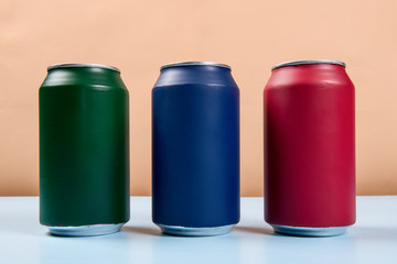 three colored cans of soft drinks closed on a light blue background