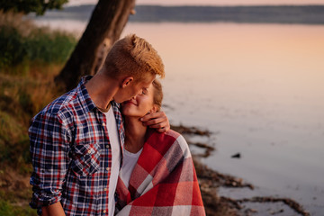 Young beautiful couple kissing at sunset at the lake