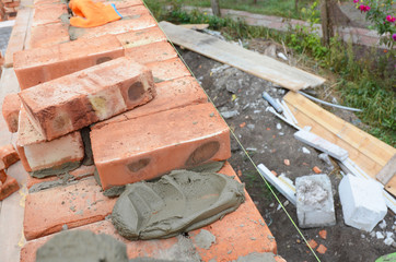 Masonry. Laying brick wall on house construction site with concrete.